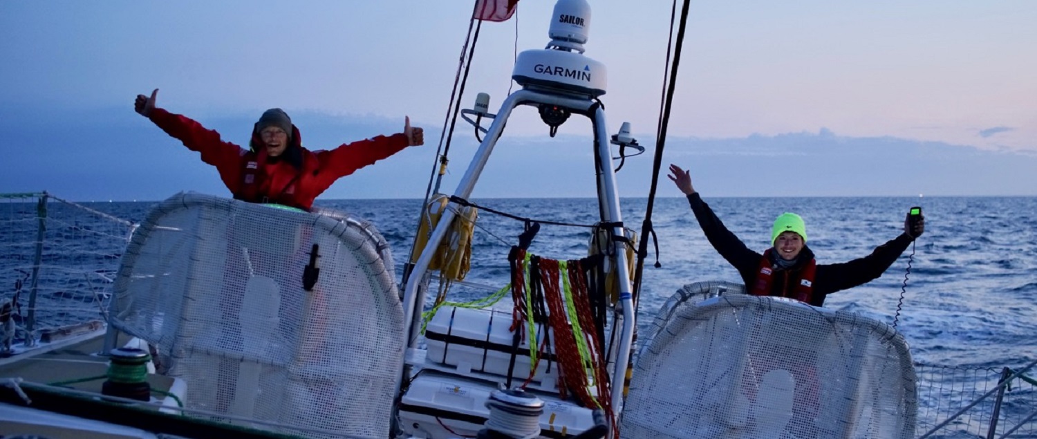 Jubilation as crew members on Sanya Serenity Coast hoist their arms aloft behind the helm stations as the near Race Finish