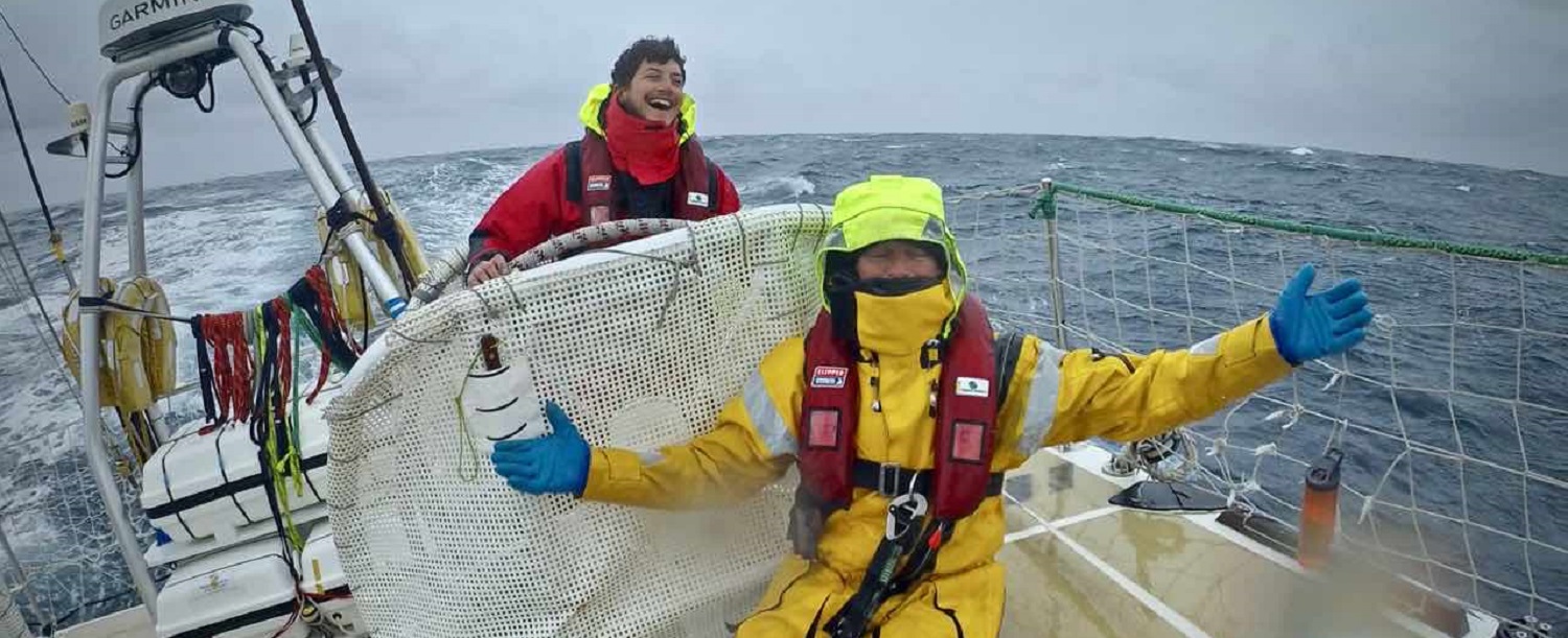 Happy helmsman on board Sanya Serenity Coast with crew member in drysuit sitting in front