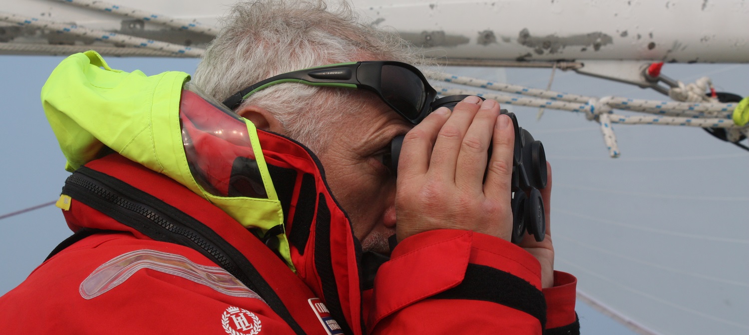 Crew member looking out through binoculars