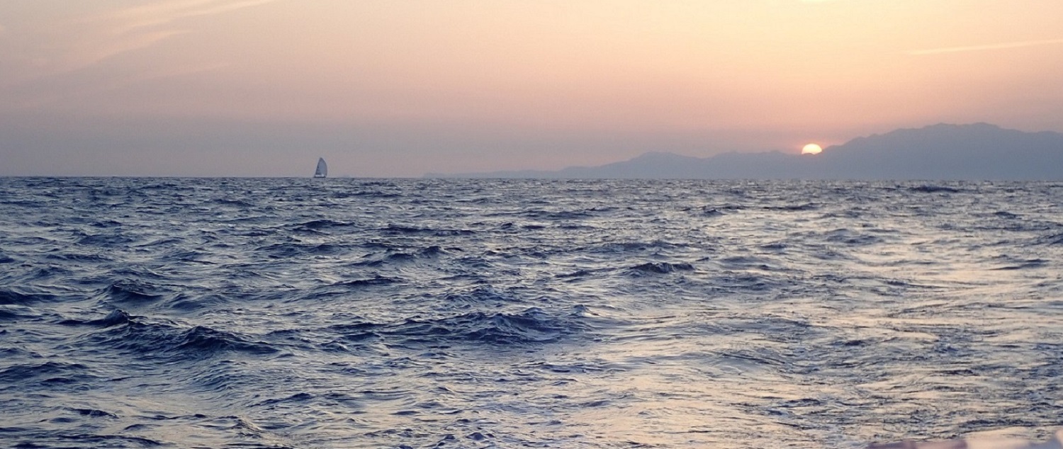 Dare To Lead pictured sailing in the distance under sunset 