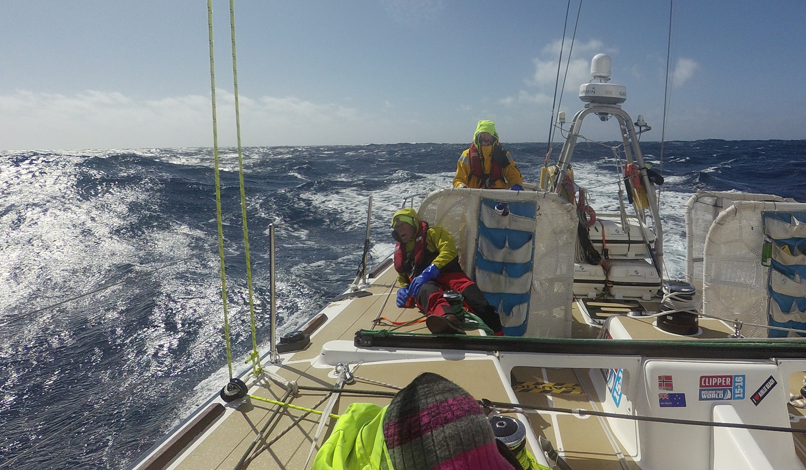 Crew shown helming in sunny, moderate conditions at sea 