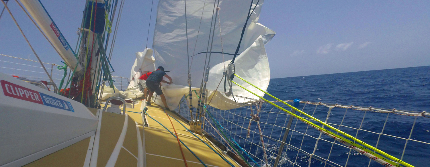 Two Nasdaq crew members pulling down the Staysail