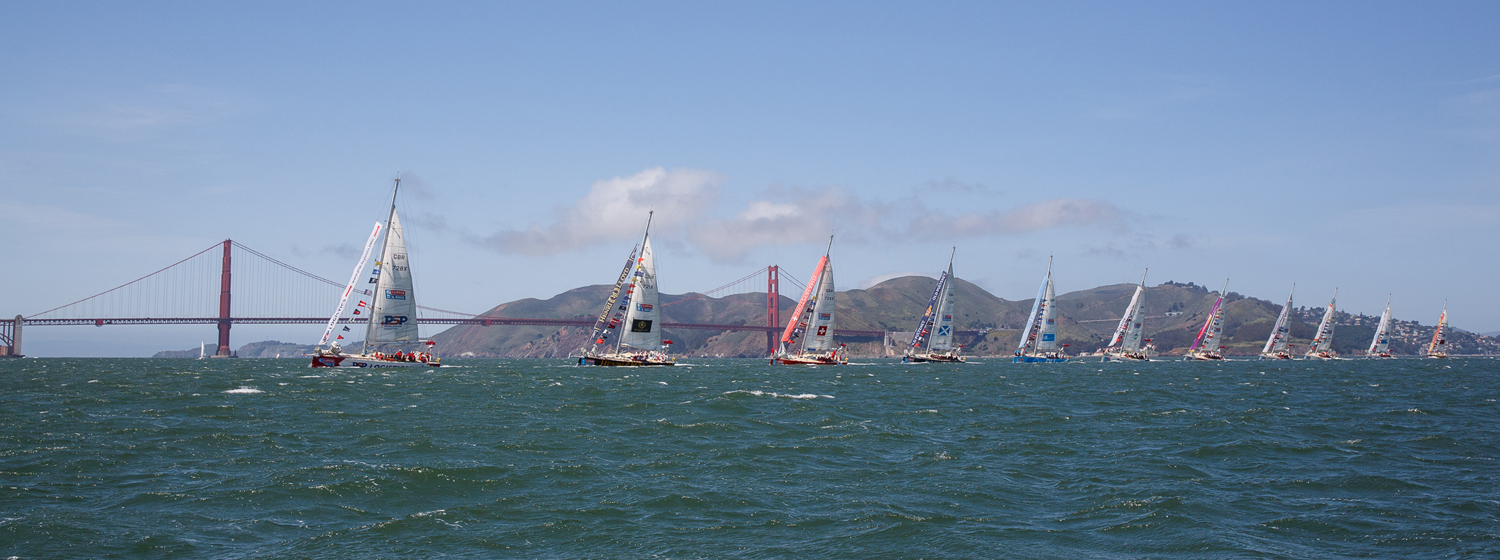 Clipper Race fleet parade of sail under Golden Gate Bridge in San Francisco