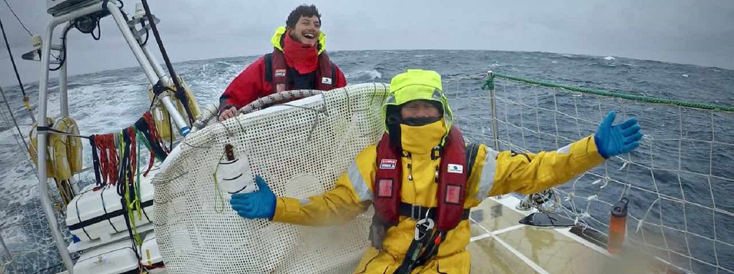 Happy helmsman on board Sanya Serenity Coast with crew member in drysuit sitting in front