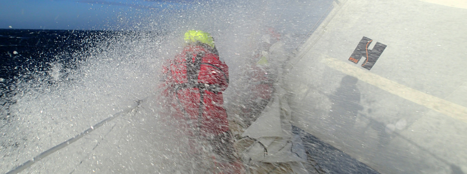 Crew member getting wet on the bow during the race to Brisbane, Australia