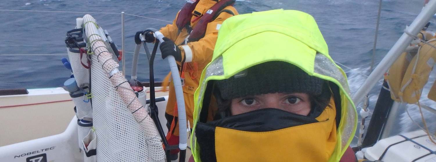 Crew member looking into camera in full foulies with just eyes showing