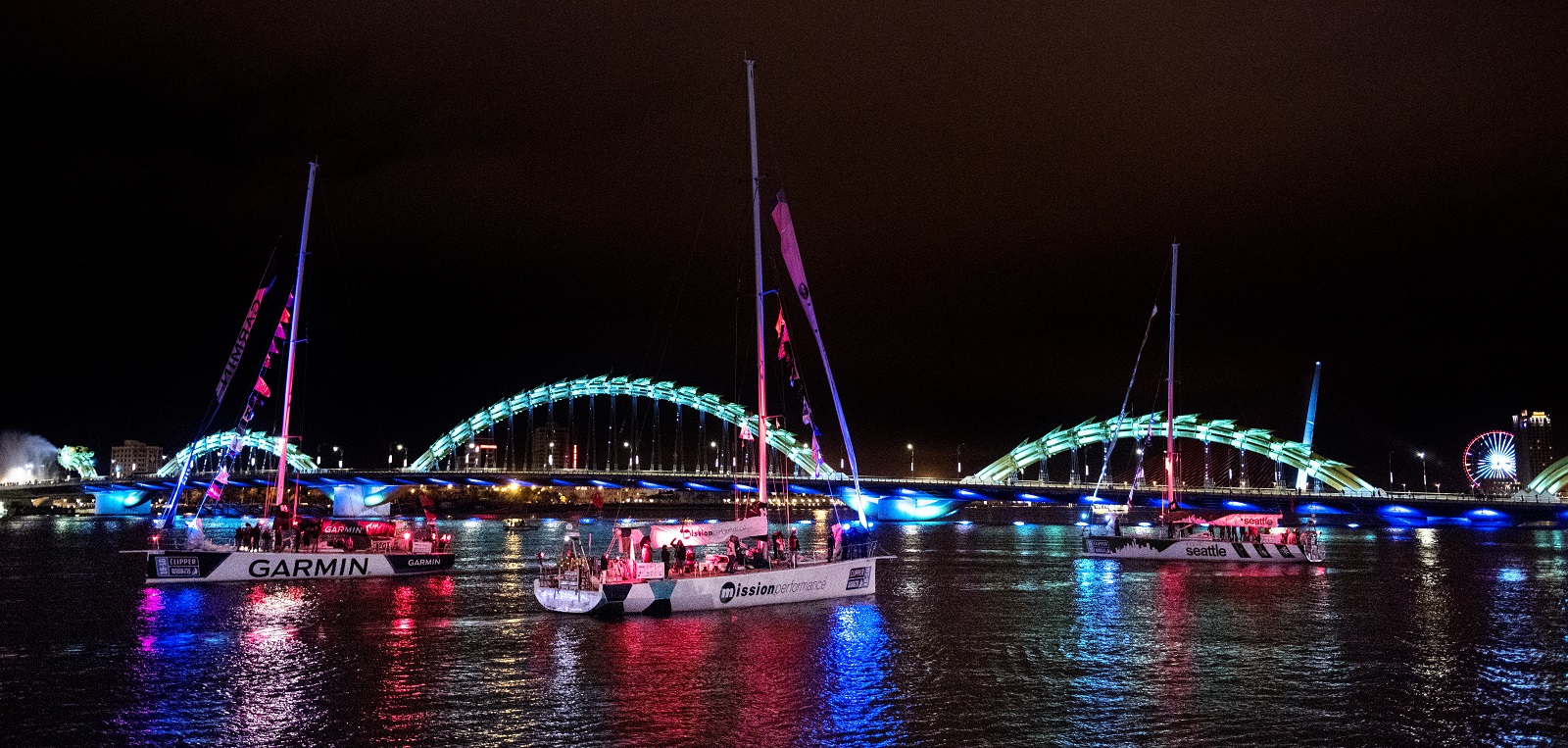 The Clipper Race fleet parades in front of the Dragon Bridge at night 